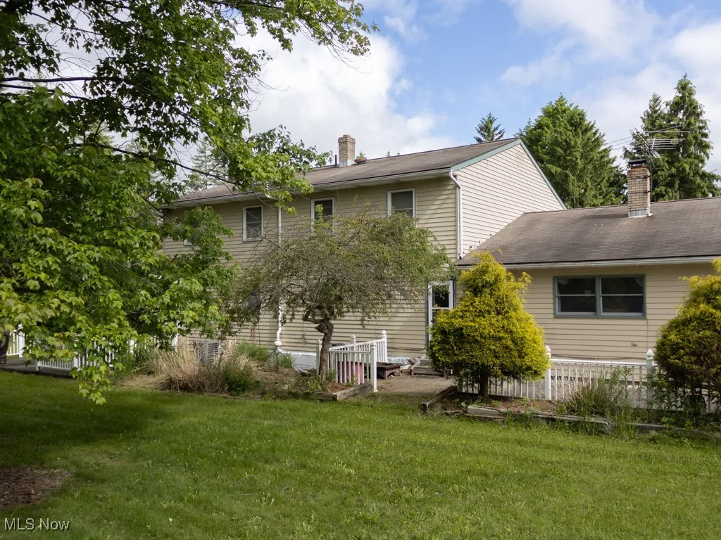 Rear view of property featuring a lawn and a chimney