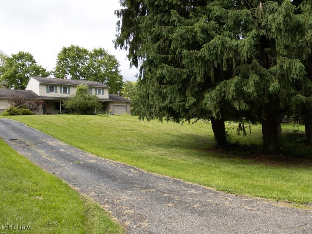 View of front of house with an attached garage, a front yard, and driveway