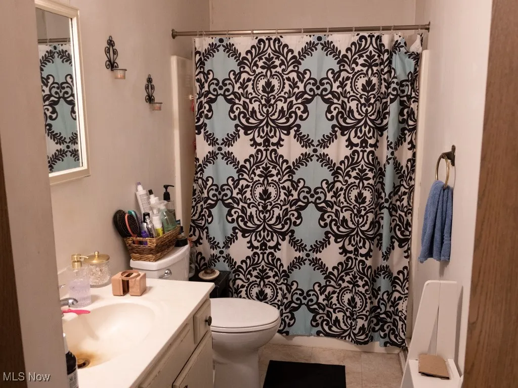 Full bath featuring vanity, curtained shower, and tile patterned floors