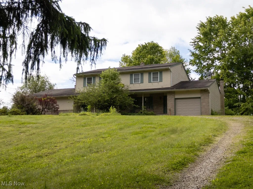 Traditional-style house featuring driveway, an attached garage, and a front yard
