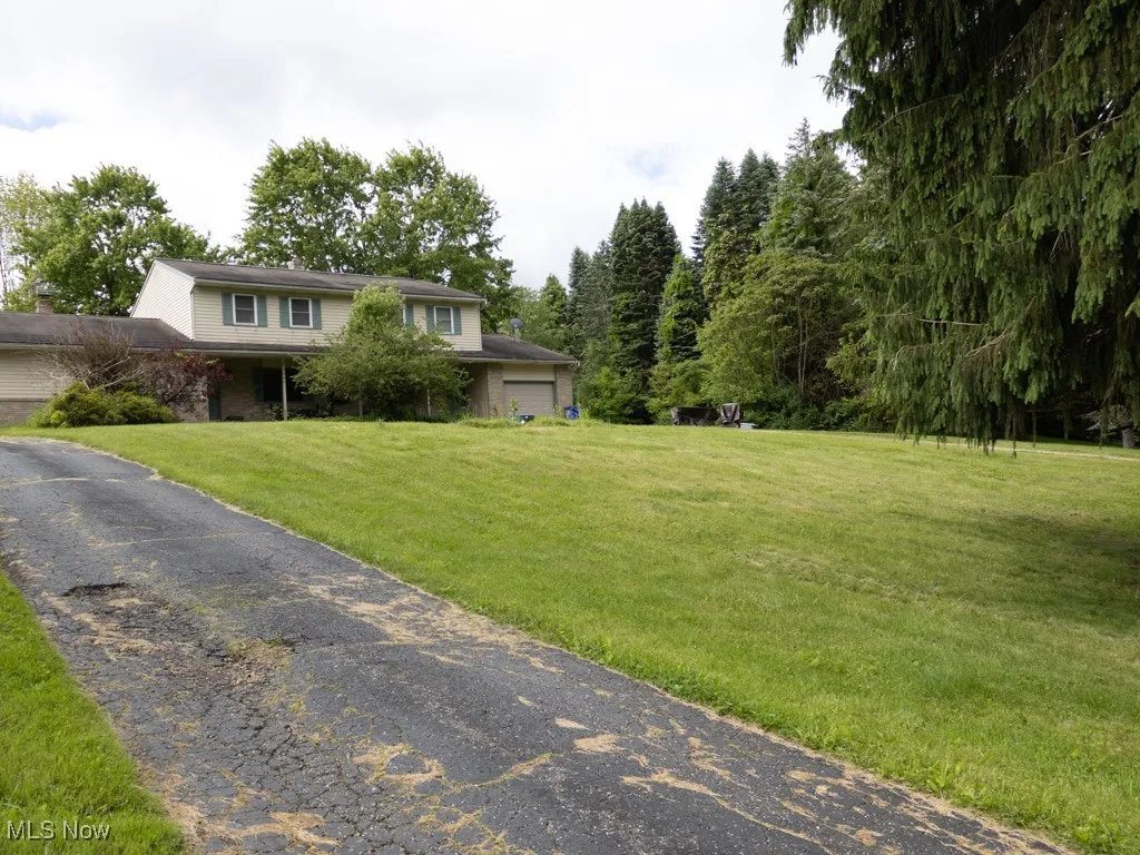 View of front of home with a garage, a front lawn, and asphalt driveway