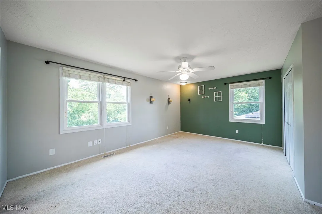 Spare room with ceiling fan, light colored carpet, and a textured ceiling