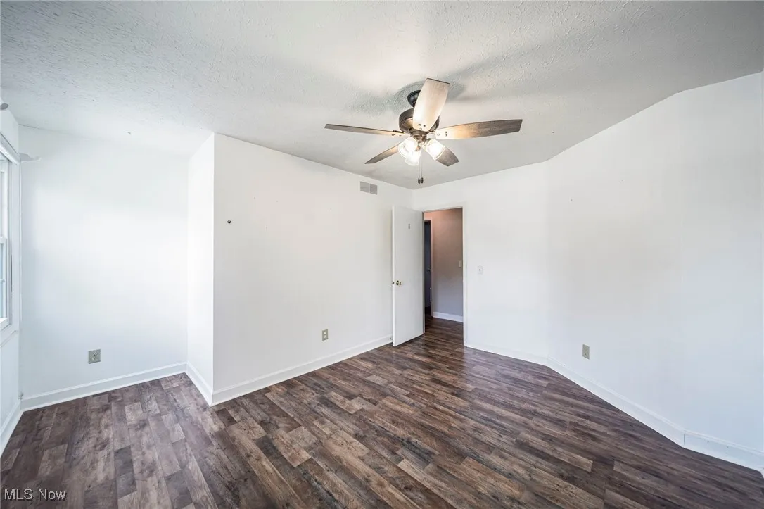 Empty room featuring wood finished floors, a ceiling fan, and a textured ceiling