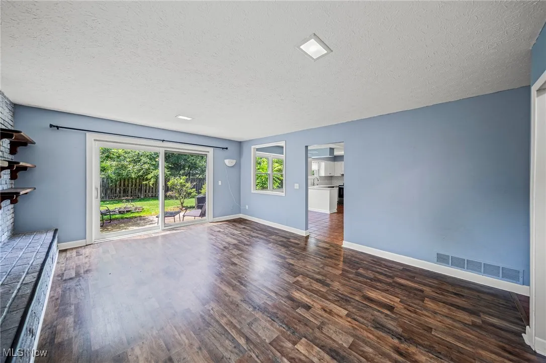 Unfurnished living room with wood finished floors and a textured ceiling