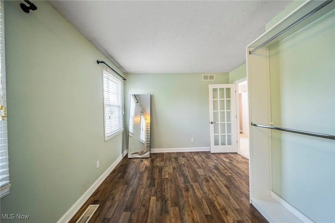 Unfurnished room with wood finished floors, a textured ceiling, and french doors