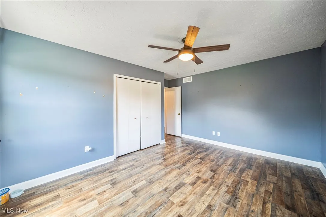 Unfurnished bedroom with wood finished floors, a closet, and ceiling fan