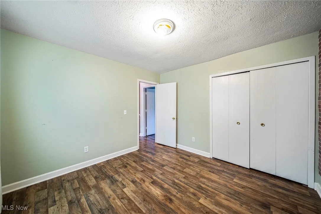 Unfurnished bedroom featuring dark wood-type flooring, a closet, and a textured ceiling