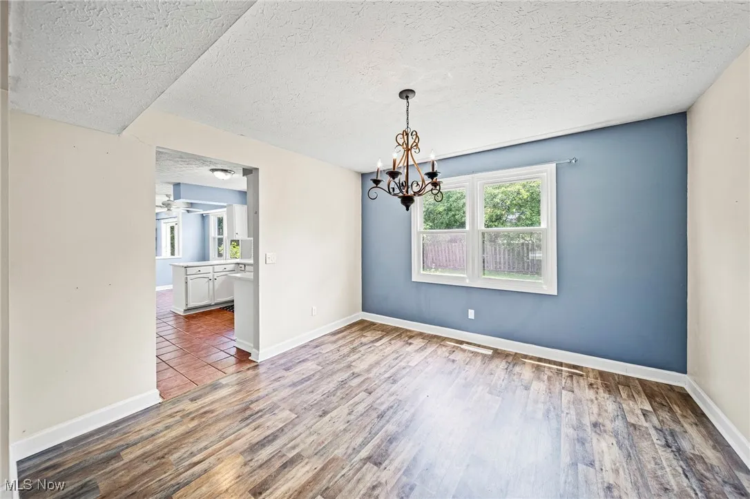 Unfurnished room featuring wood finished floors, a chandelier, and a textured ceiling