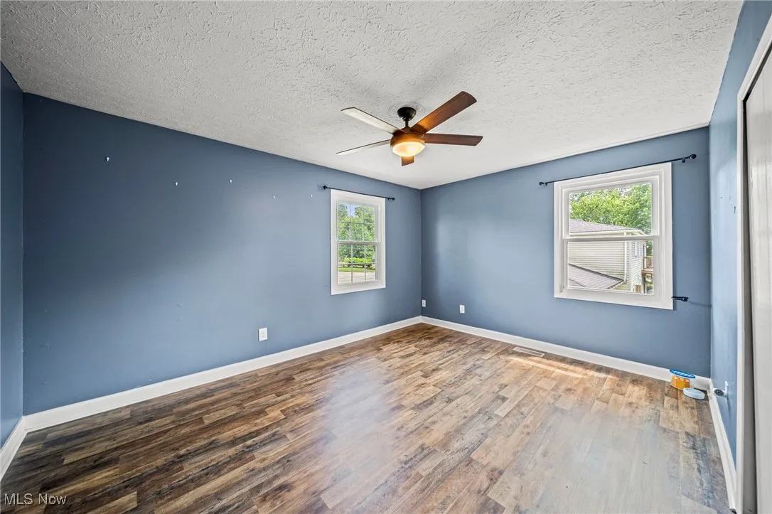 Spare room featuring wood finished floors, a ceiling fan, and a textured ceiling