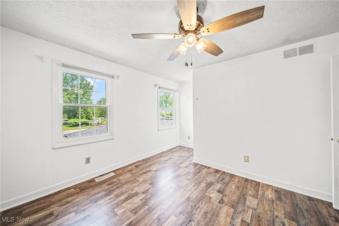 Empty room with wood finished floors, a textured ceiling, and ceiling fan