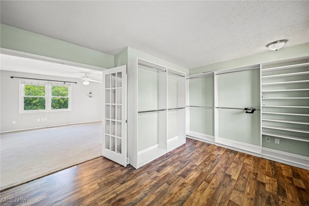 Spacious closet featuring wood finished floors, french doors, and ceiling fan