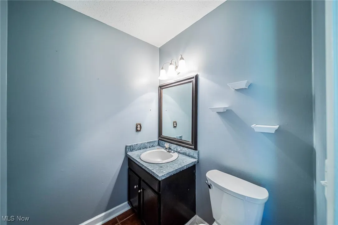 Half bath with vanity and a textured ceiling