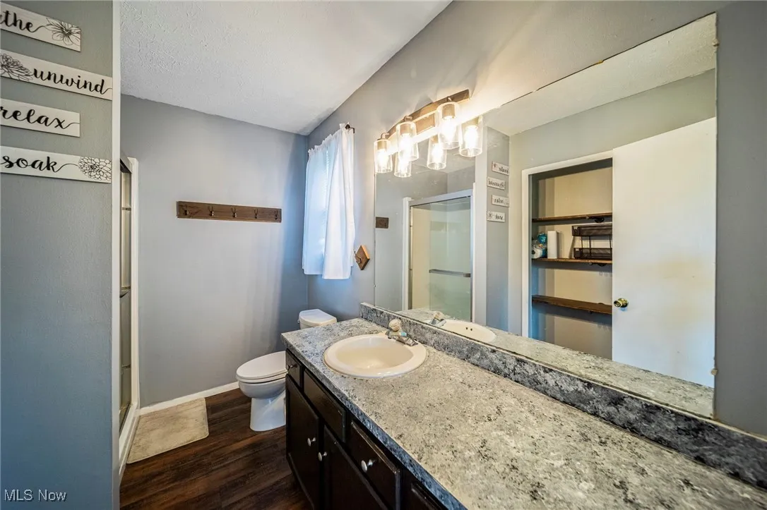 Full bathroom with a shower stall, wood finished floors, vanity, and a textured ceiling