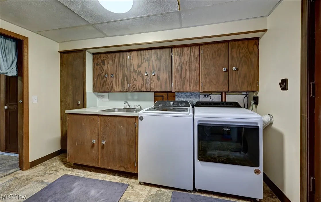 Laundry area with cabinet space, washer and dryer, and light stone finish floors