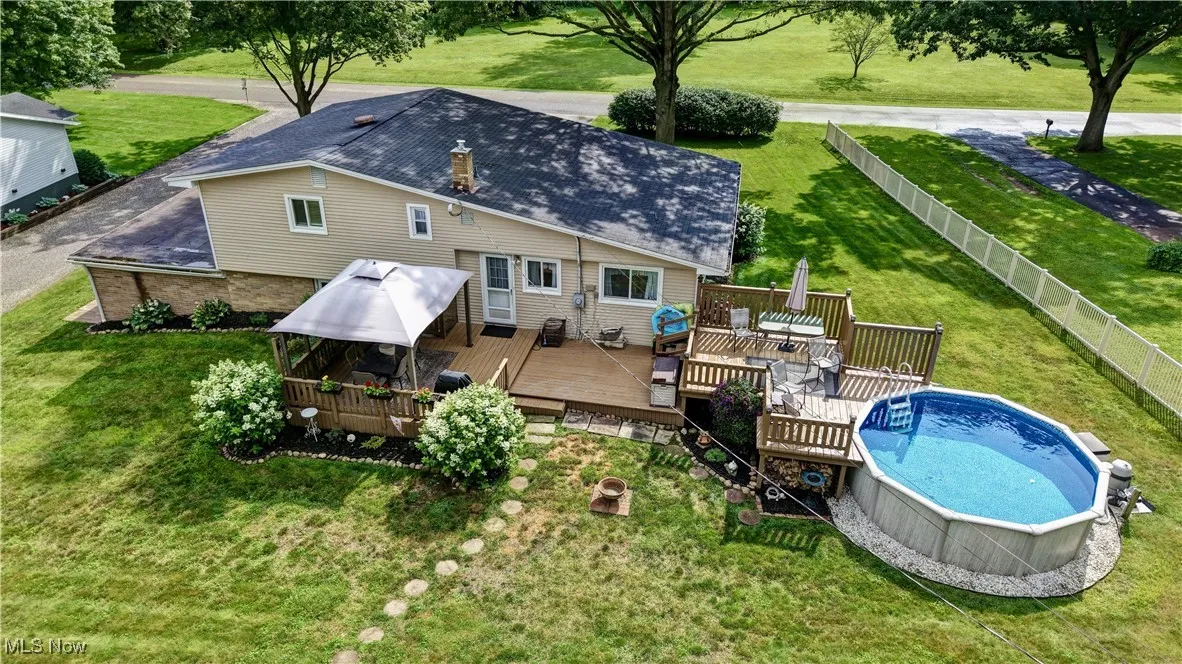 Back of property featuring a wooden deck and an outdoor pool