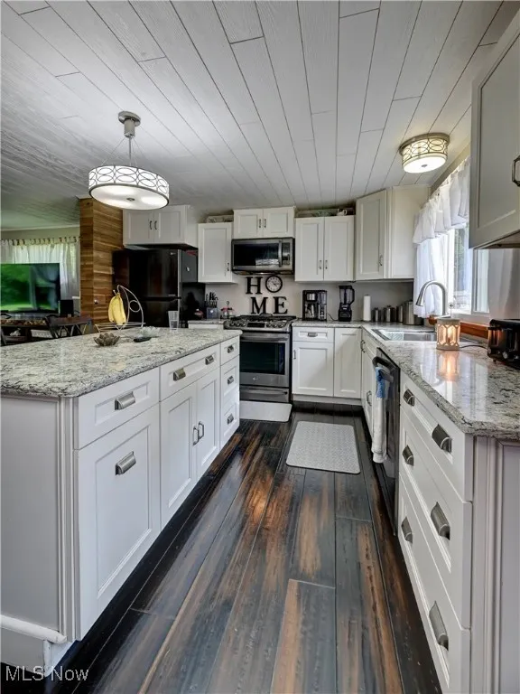 Kitchen featuring black appliances, dark wood-style floors, white cabinetry, decorative light fixtures, and light stone countertops