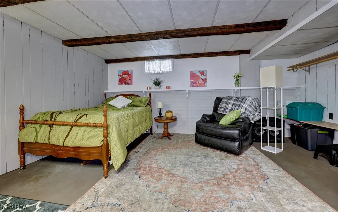 Bedroom with concrete floors, beamed ceiling, and wooden walls