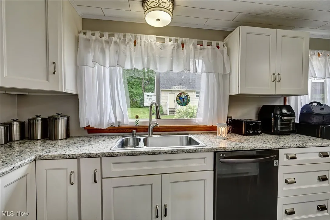 Kitchen with dishwasher, plenty of natural light, white cabinets, and crown molding