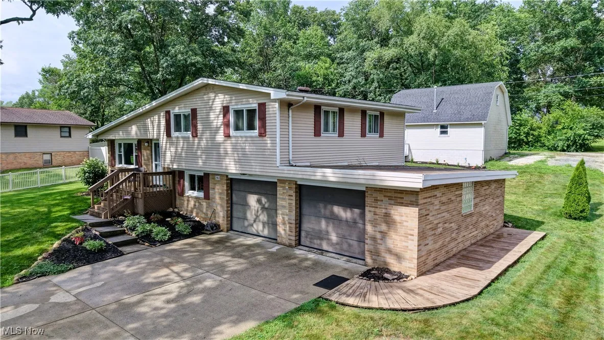 View of front of house with an attached garage, driveway, and view of wooded area