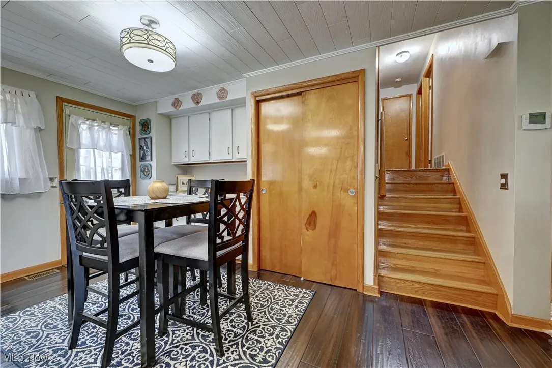 Dining room with dark wood-style flooring, stairway, and ornamental molding