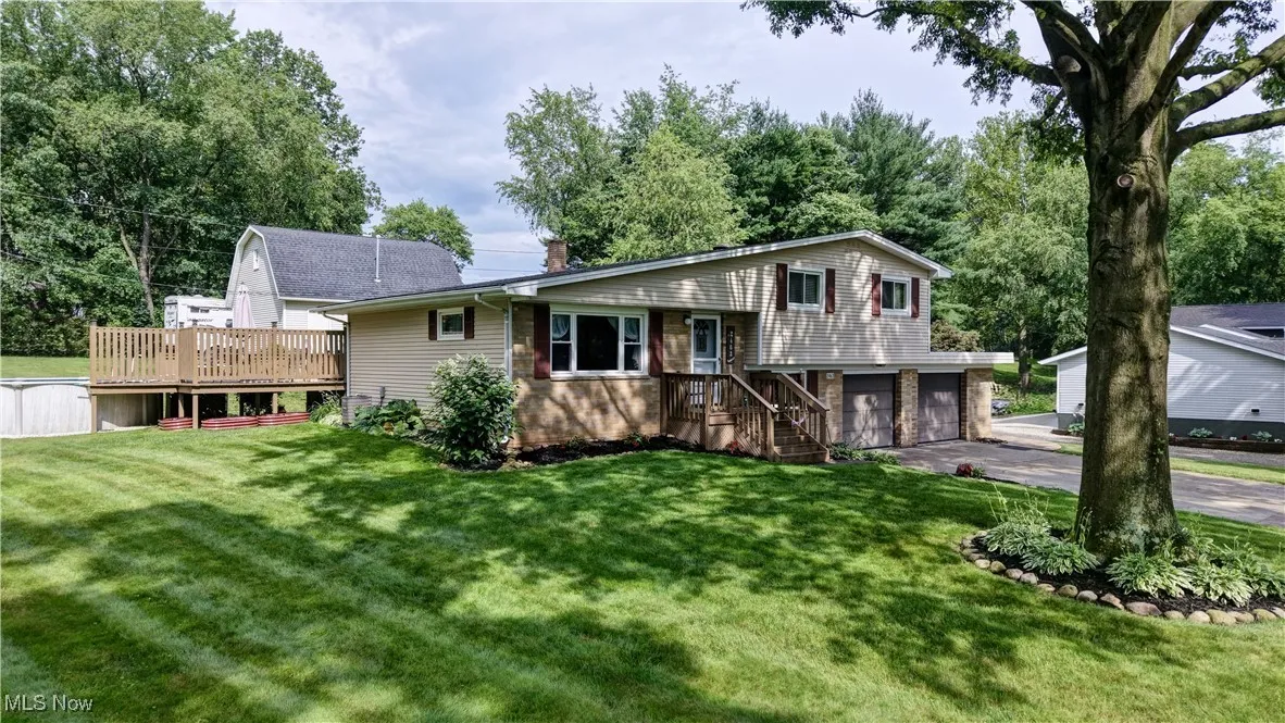 Tri-level home featuring a garage, a front lawn, driveway, and a deck