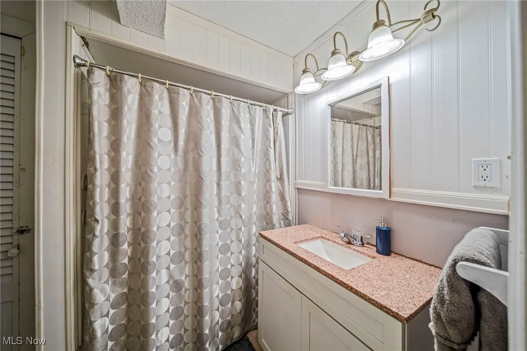 Bathroom featuring vanity, a shower with shower curtain, and a decorative wall
