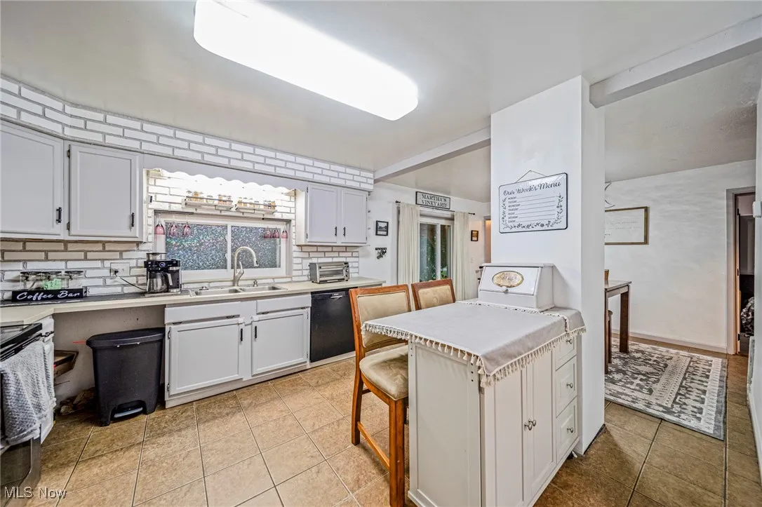 Kitchen featuring black dishwasher, stainless steel electric range, decorative backsplash, light countertops, and light tile patterned floors