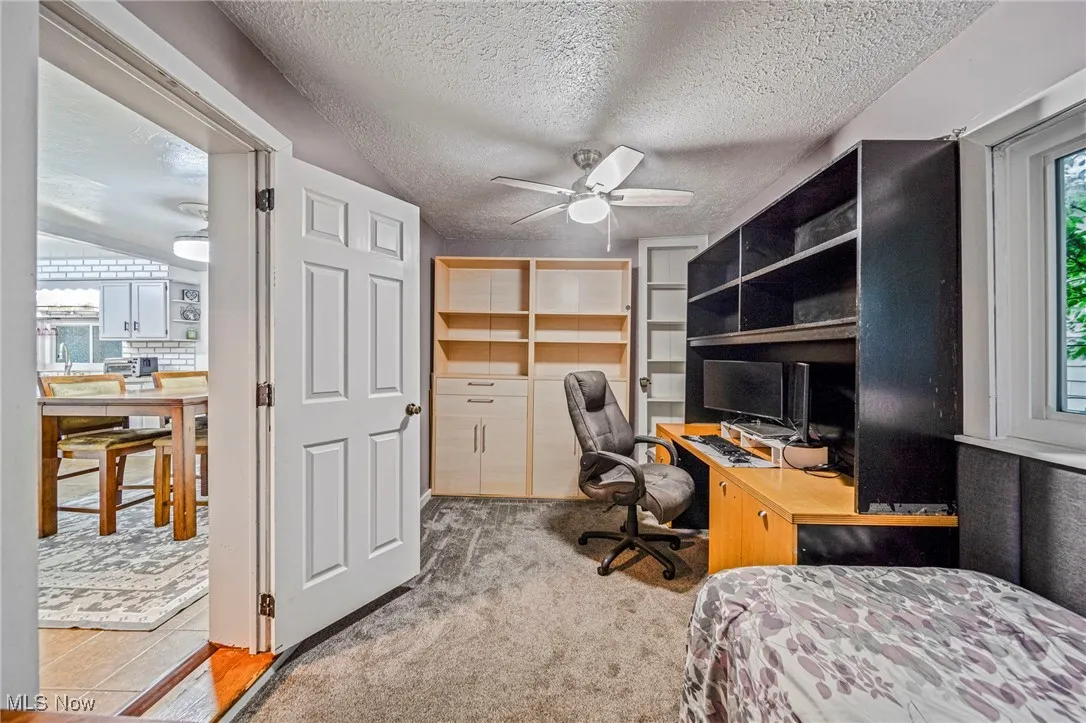 Bedroom with a desk, a textured ceiling, and a ceiling fan