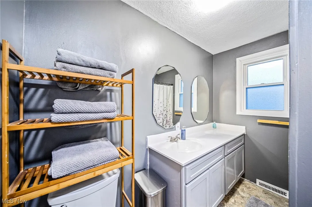 Bathroom with vanity, a textured ceiling, and stone finish floors