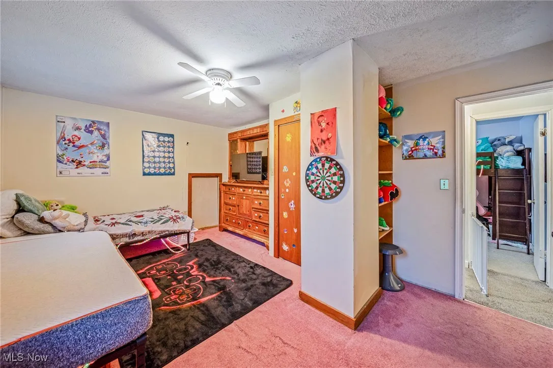 Carpeted bedroom with a textured ceiling and a ceiling fan