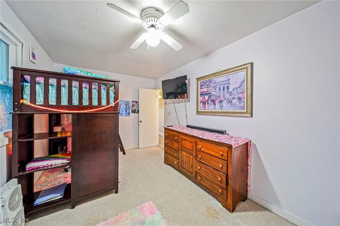 Bedroom featuring light carpet, a textured ceiling, and a ceiling fan