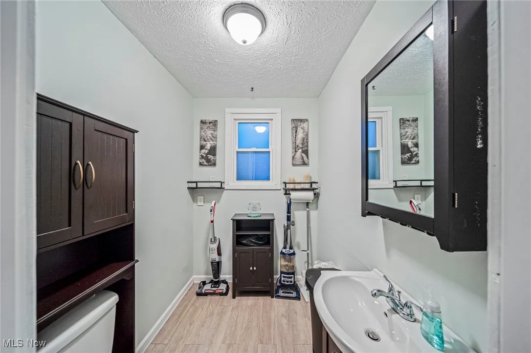 Bathroom with a textured ceiling, wood finished floors, and vanity