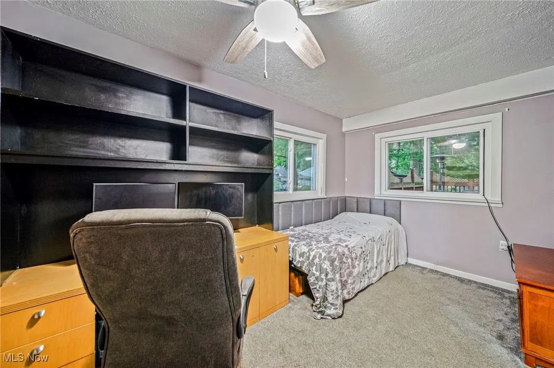 Bedroom with a textured ceiling, carpet flooring, and a ceiling fan
