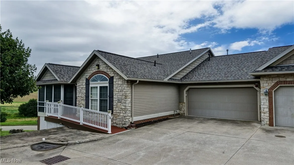 View of front of house with stone siding, a shingled roof, concrete driveway, and an attached garage