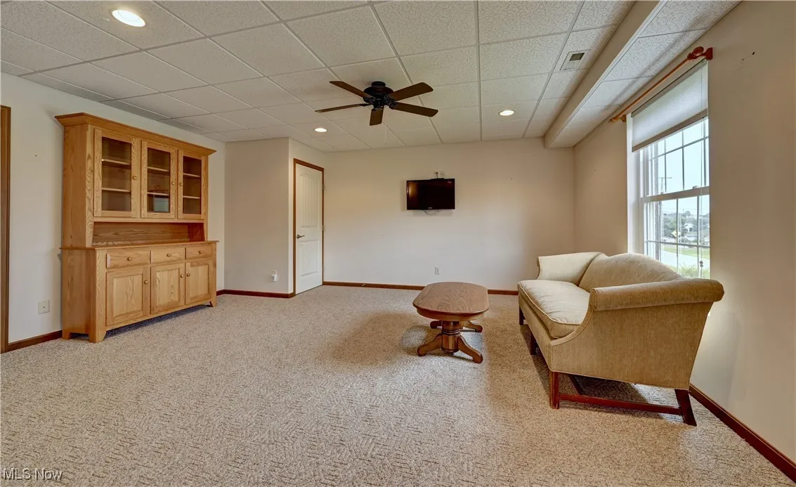 Living area featuring light carpet, ceiling fan, a paneled ceiling, and recessed lighting