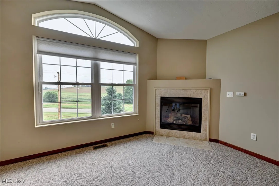 Unfurnished living room with carpet floors and a tile fireplace
