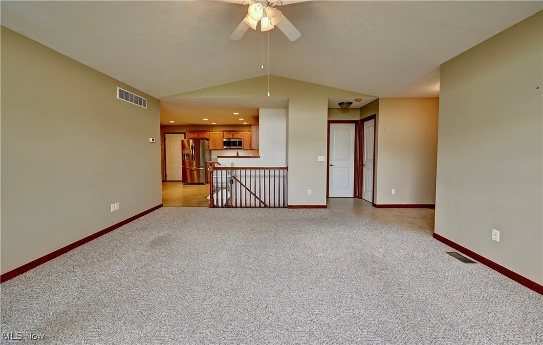 Unfurnished living room with lofted ceiling, ceiling fan, and light carpet