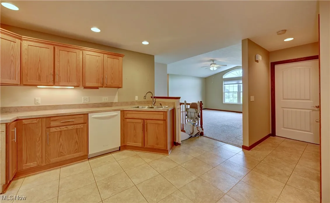 Kitchen featuring white dishwasher, a peninsula, ceiling fan, light countertops, and light tile patterned flooring