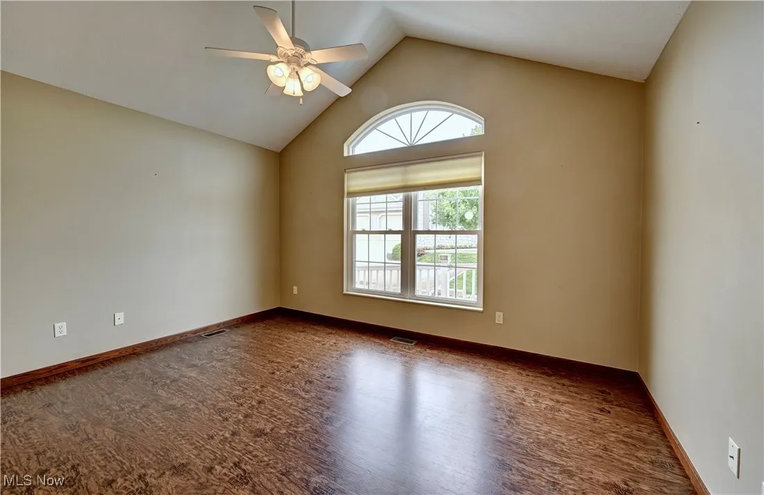 Empty room with ceiling fan, wood finished floors, and high vaulted ceiling