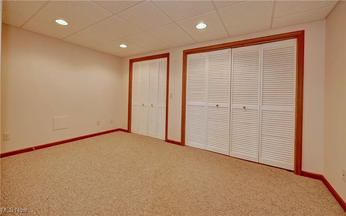 Unfurnished bedroom with carpet floors, recessed lighting, a paneled ceiling, and multiple closets