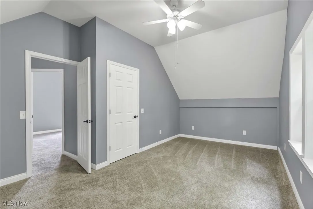 Bonus room with vaulted ceiling, carpet flooring, and a ceiling fan