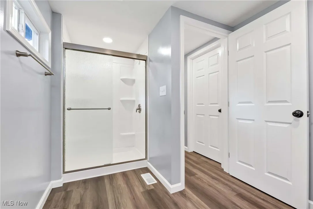 Full bath featuring a shower stall, wood finished floors, and recessed lighting