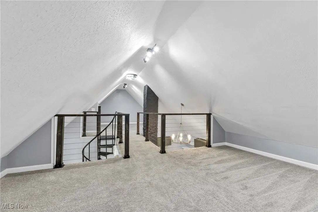 Additional living space featuring vaulted ceiling, a textured ceiling, and carpet floors