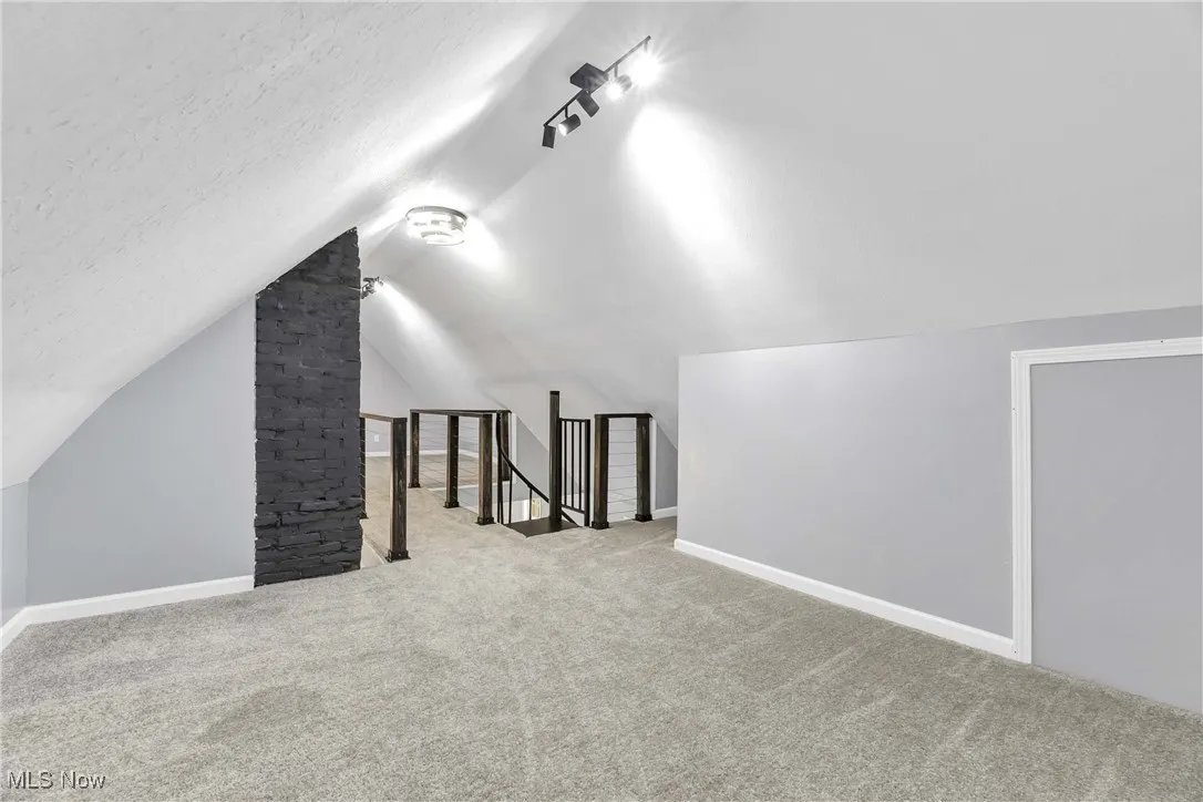 Additional living space with carpet flooring, vaulted ceiling, and a textured ceiling