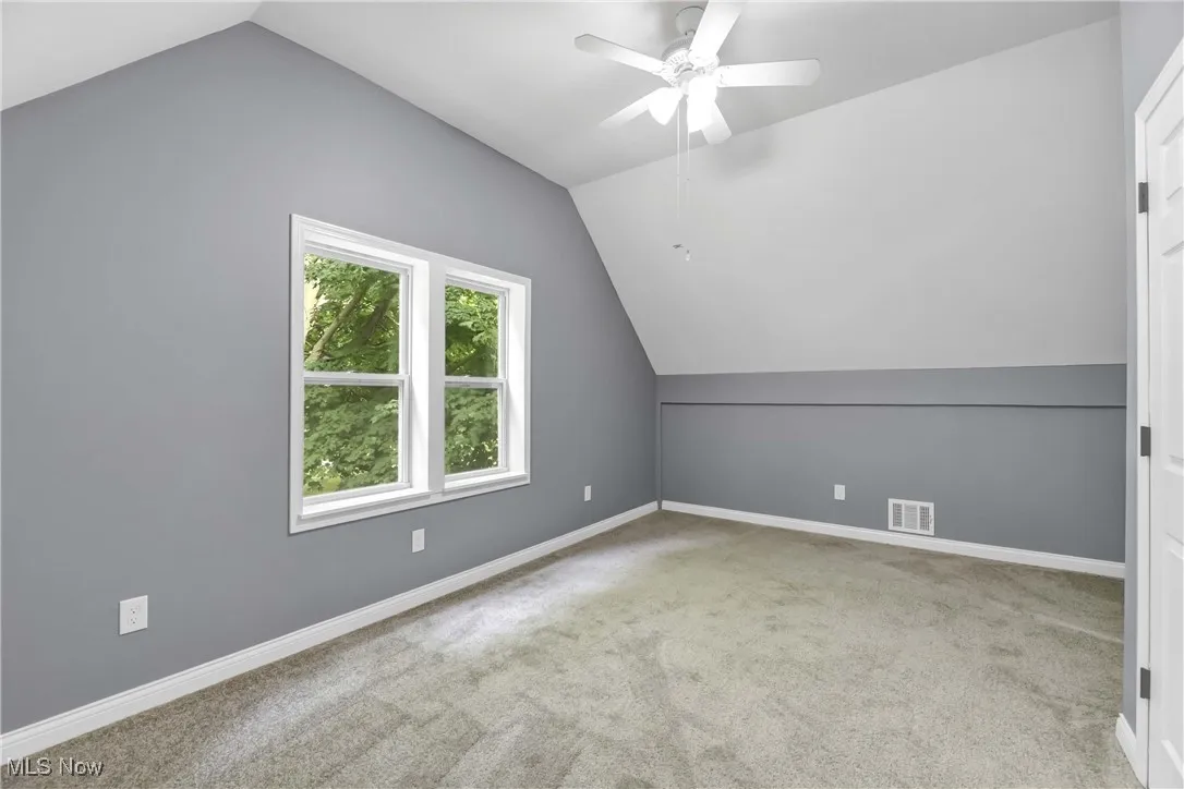 Additional living space featuring vaulted ceiling, carpet flooring, and a ceiling fan