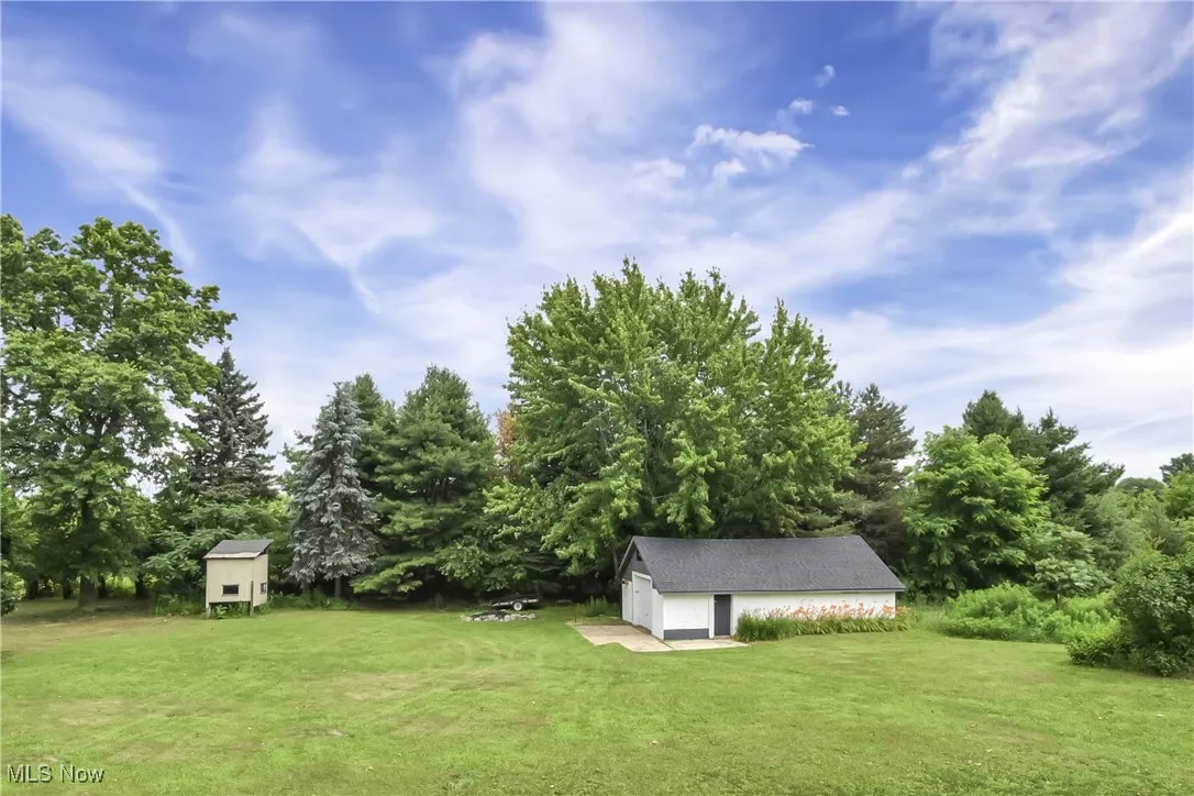 View of green lawn featuring an outdoor structure and a garage