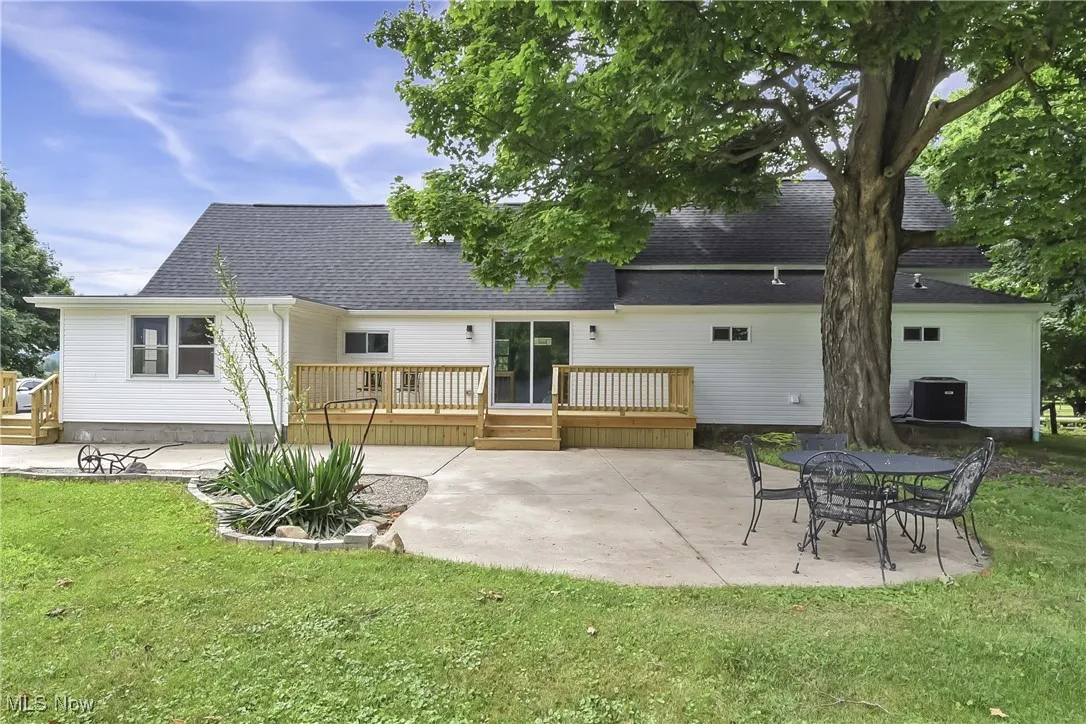 Rear view of house featuring roof with shingles, a patio area, and a yard