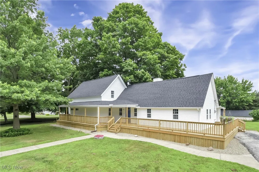 View of front of property with a shingled roof, a chimney, a front yard, and covered porch