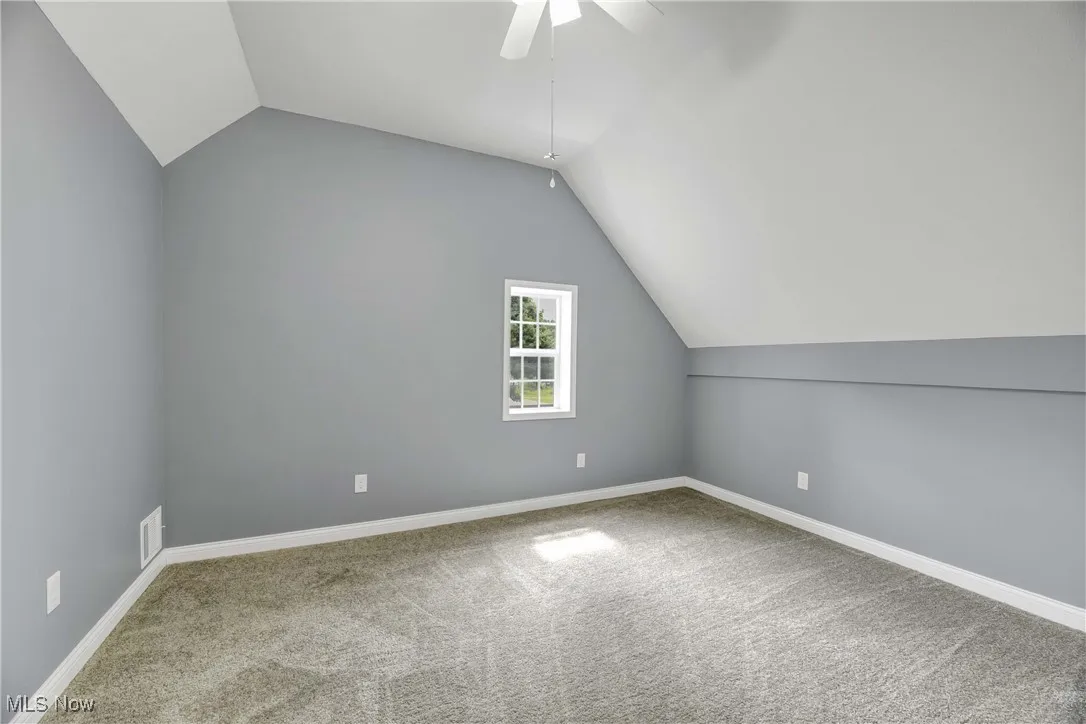 Additional living space with ceiling fan, carpet, and lofted ceiling