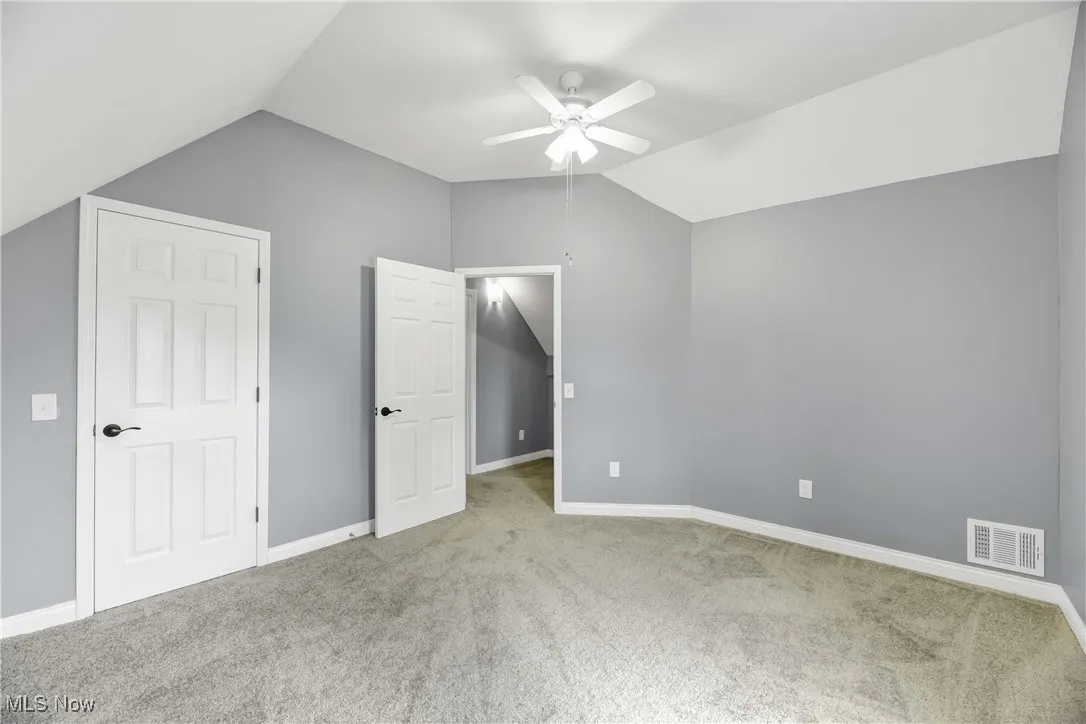 Unfurnished bedroom with lofted ceiling, carpet floors, and a ceiling fan